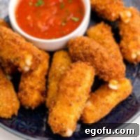 Square image close up of Homemade Mozzarella Sticks on black plate with sauce.