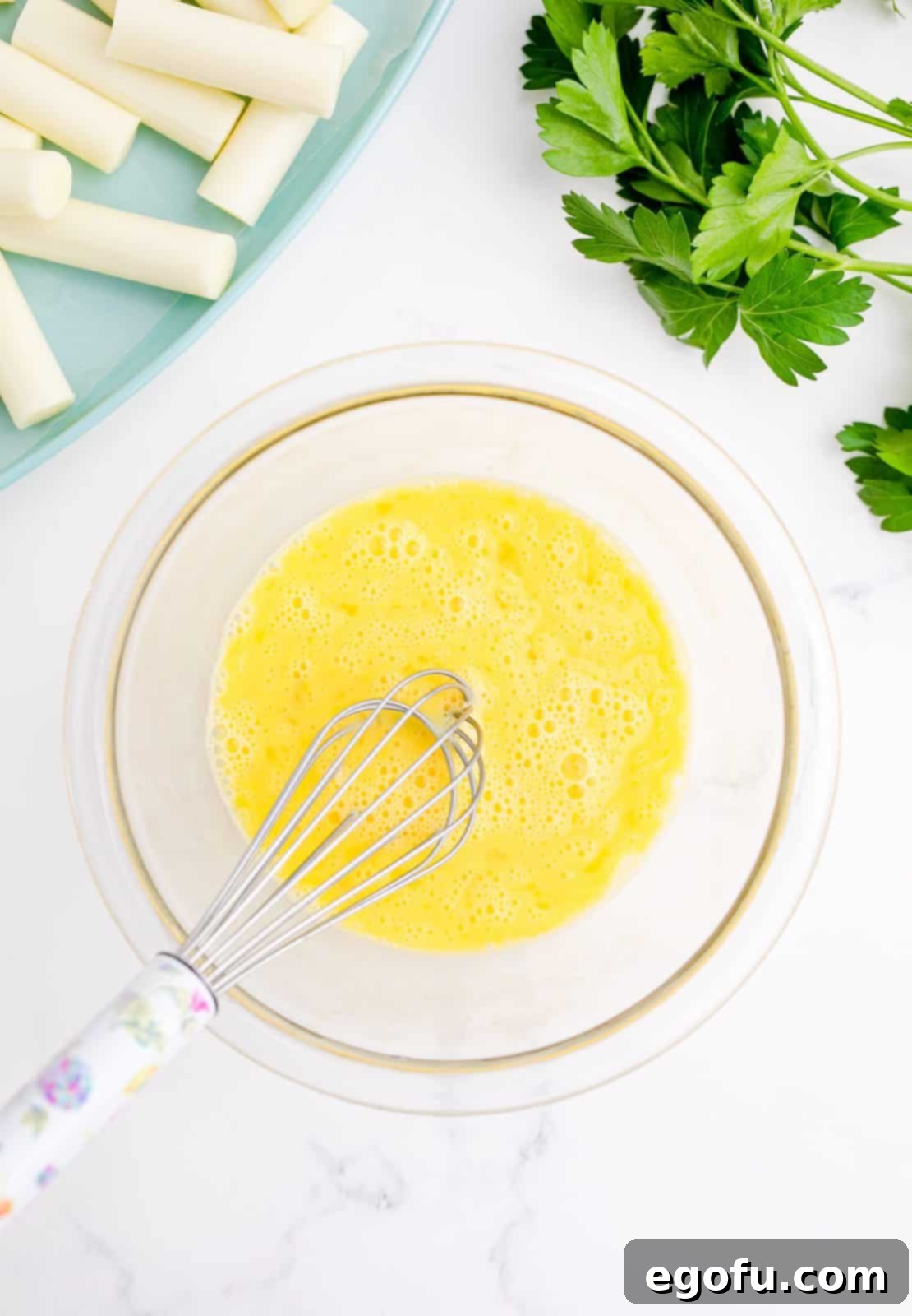 Eggs and water whisked together i bowl.