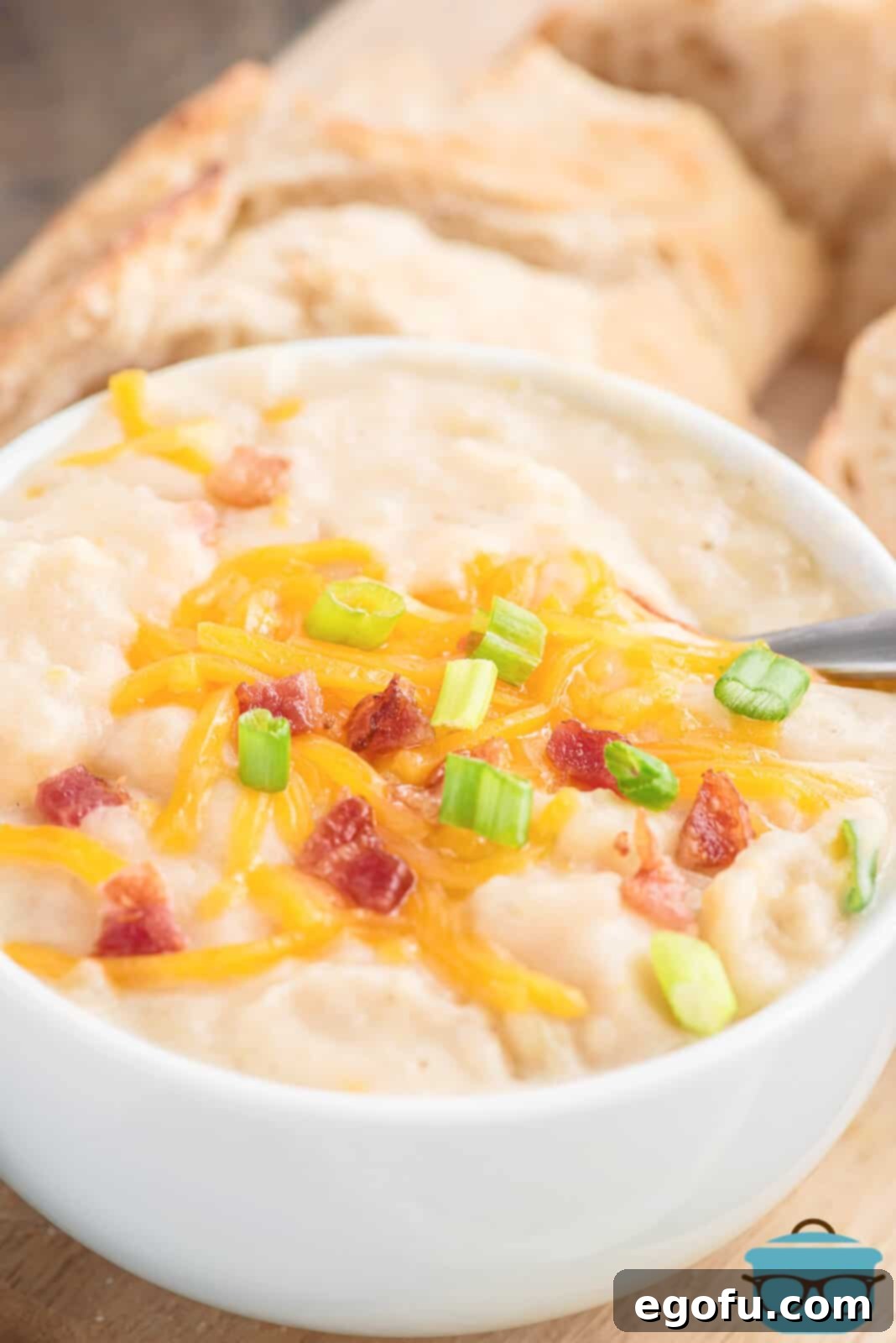 Slow Cooker Creamy Potato Bliss 2 A steaming white bowl of creamy potato soup, garnished generously with golden crispy bacon, vibrant shredded cheddar cheese, and freshly sliced green onions, ready to be enjoyed.