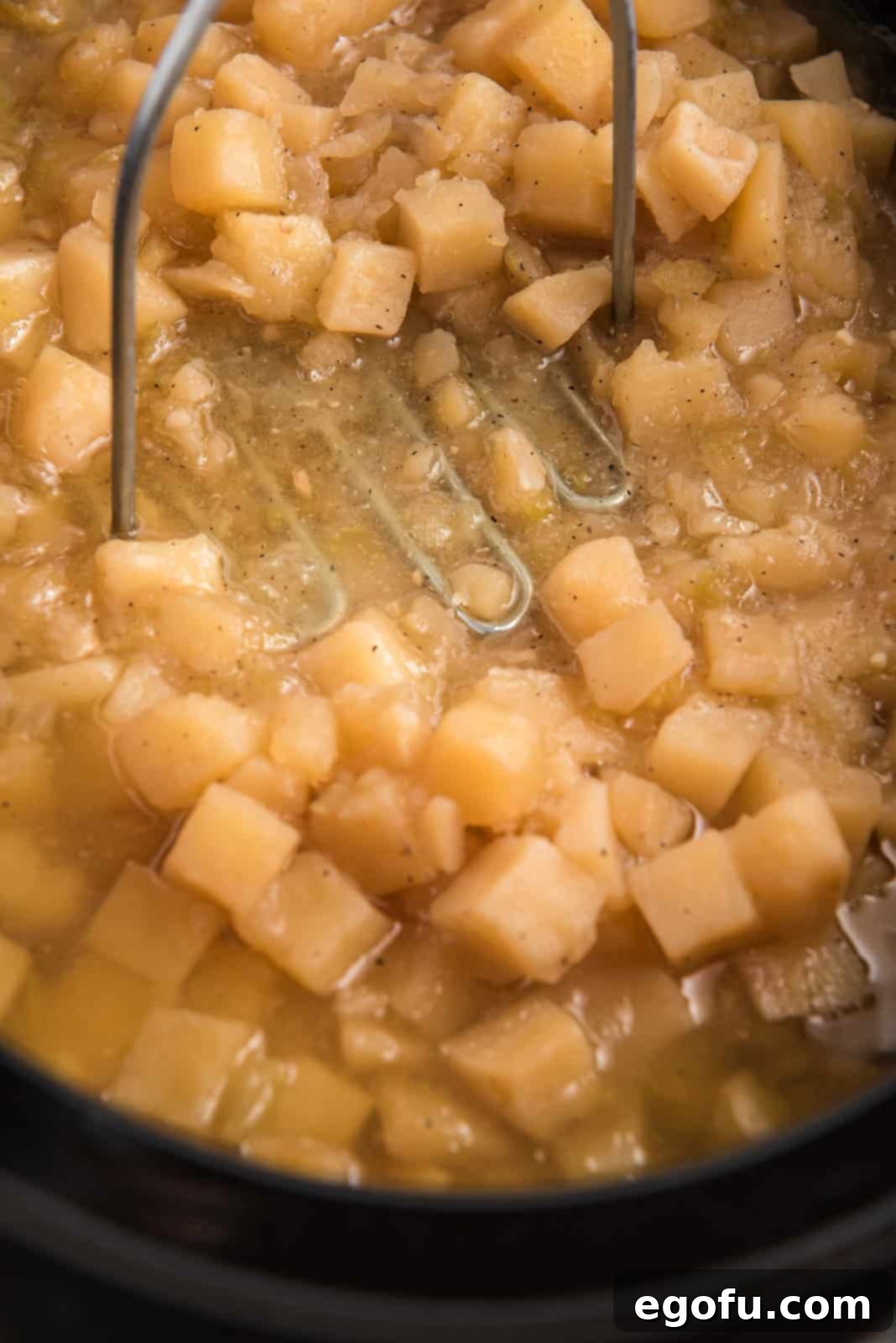 Slow Cooker Creamy Potato Bliss 7 A potato masher is used to gently mash tender cooked potatoes within the slow cooker, creating a creamy soup with delightful chunky texture.