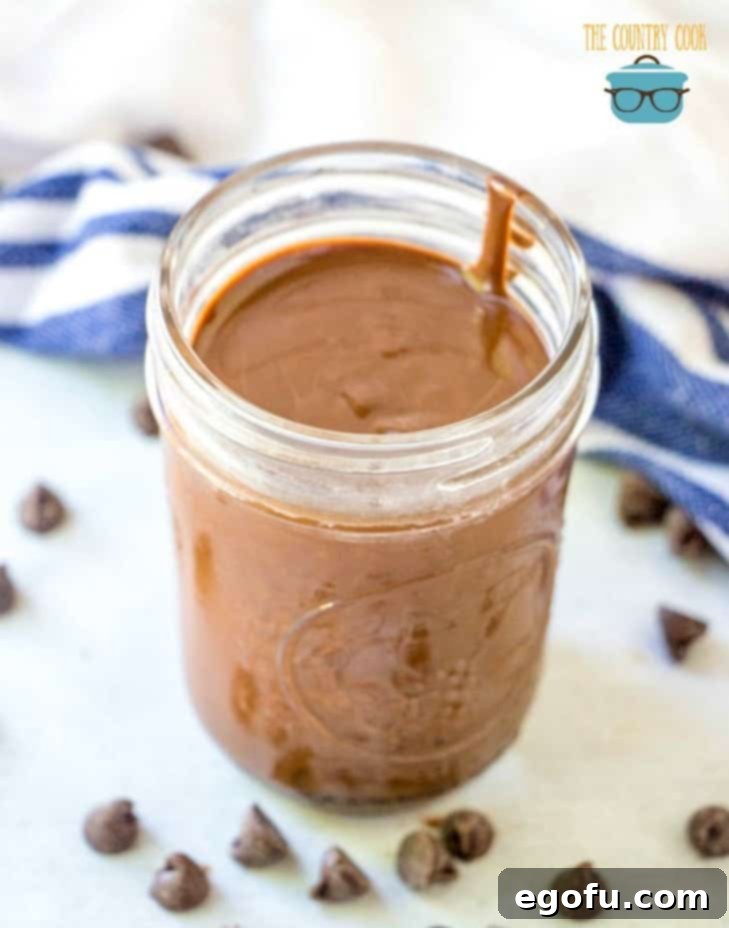 liquid Homemade Chocolate Magic Shell in a small mason jar shown with chocolate chips sprinkled around the jar.