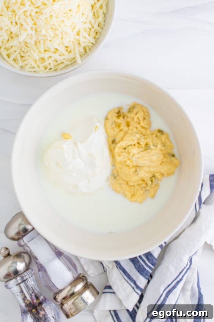 A white mixing bowl containing sour cream, milk, and cream of chicken soup, perfectly combined to form the creamy base.