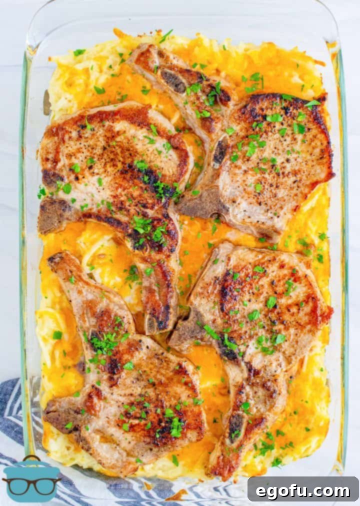 A full, vibrant photo of the baked pork chop hash brown casserole in a glass rectangular baking dish, golden-brown and bubbling hot from the oven.