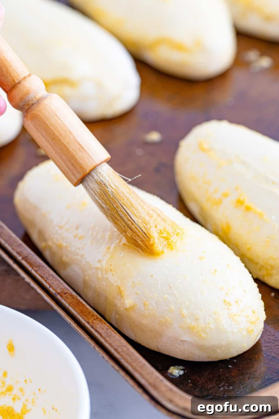 brushing breadsticks with garlic butter mixture using a pastry brush. 