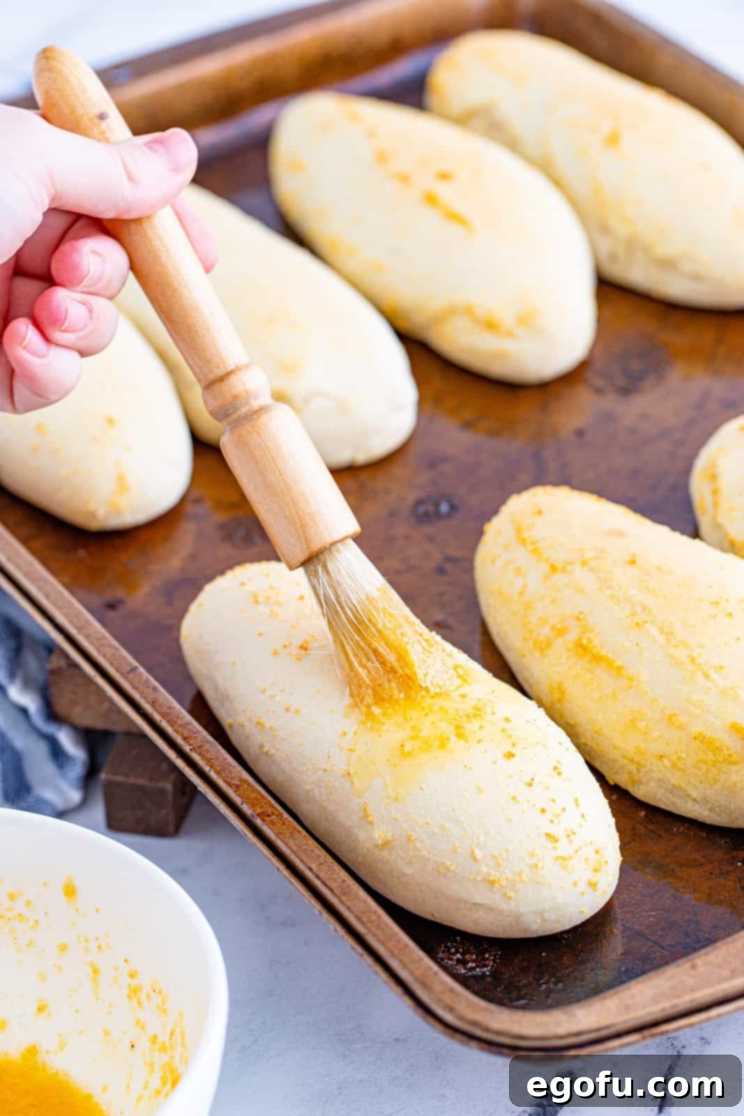 brushing garlic butter on breadsticks.