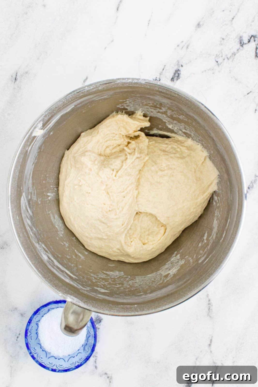 dough in a mixing bowl that has been kneaded with a hook dough attachment. 