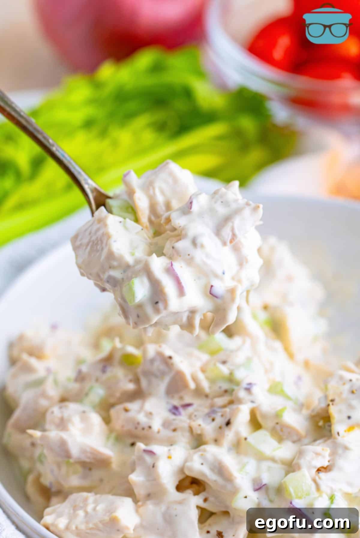 A spoon scooping some Chicken Salad out of the bowl.