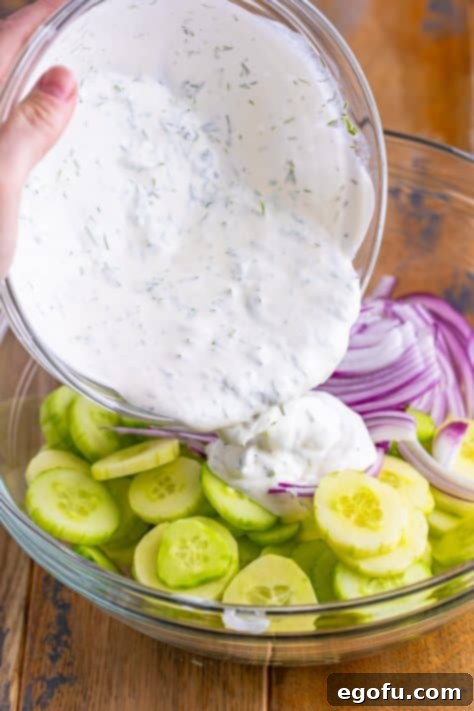 Chilled Cucumber Delight 12 Creamy dressing being poured over a bowl of fresh cucumbers and onions.