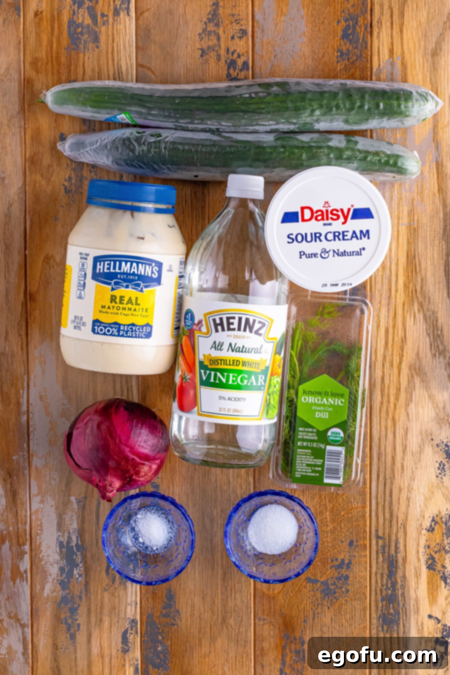 Chilled Cucumber Delight 5 A flat lay photograph showcasing all the fresh ingredients for Creamy Cucumber Salad: English cucumbers, mayonnaise, sour cream, white vinegar, red onion, salt, sugar, and fresh dill.