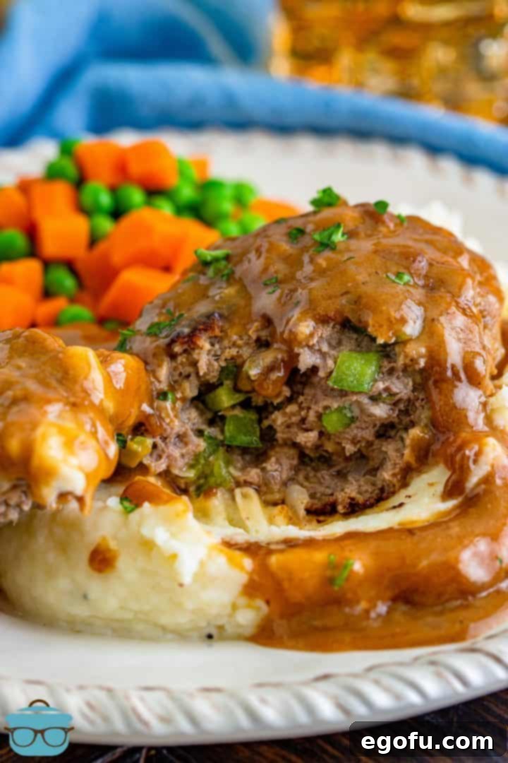 a hamburger steak cut open to see the inside filled with green peppers and onions.