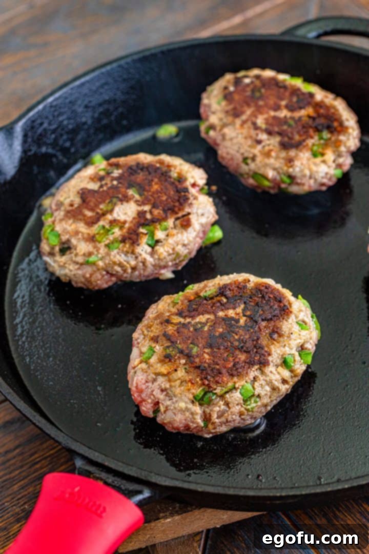 browning hamburger patties in a cast iron skillet. 