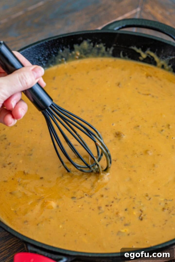 a whisk mixing together gravy mix in cast iron pan.