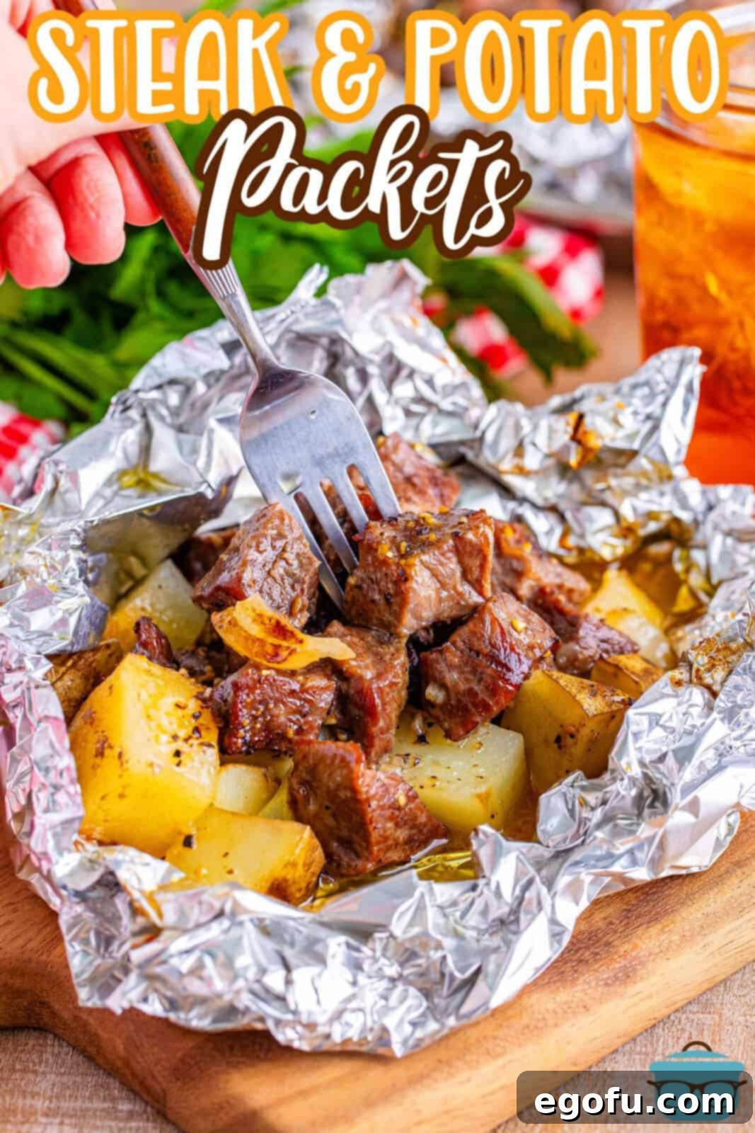 a fork shown being inserted into a piece of cooked steak and potatoes in a foil packet. 