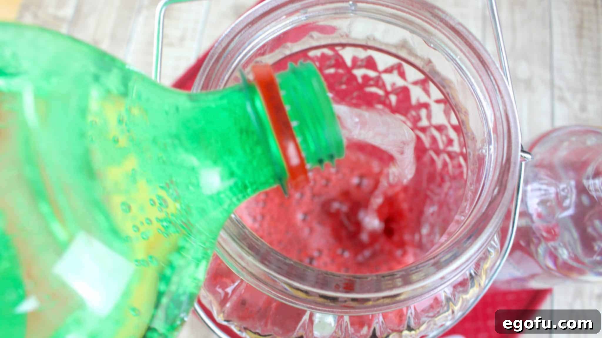 Effervescent Strawberry Bliss 6 pouring 7-Up soda into the strawberry concentrate mixture in a large container.
