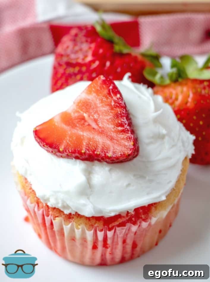 Strawberry Burst Poke Cupcakes 2 Individual Strawberry Jell-O Poke Cupcake on a white round plate, showcasing its moist texture and vibrant color.