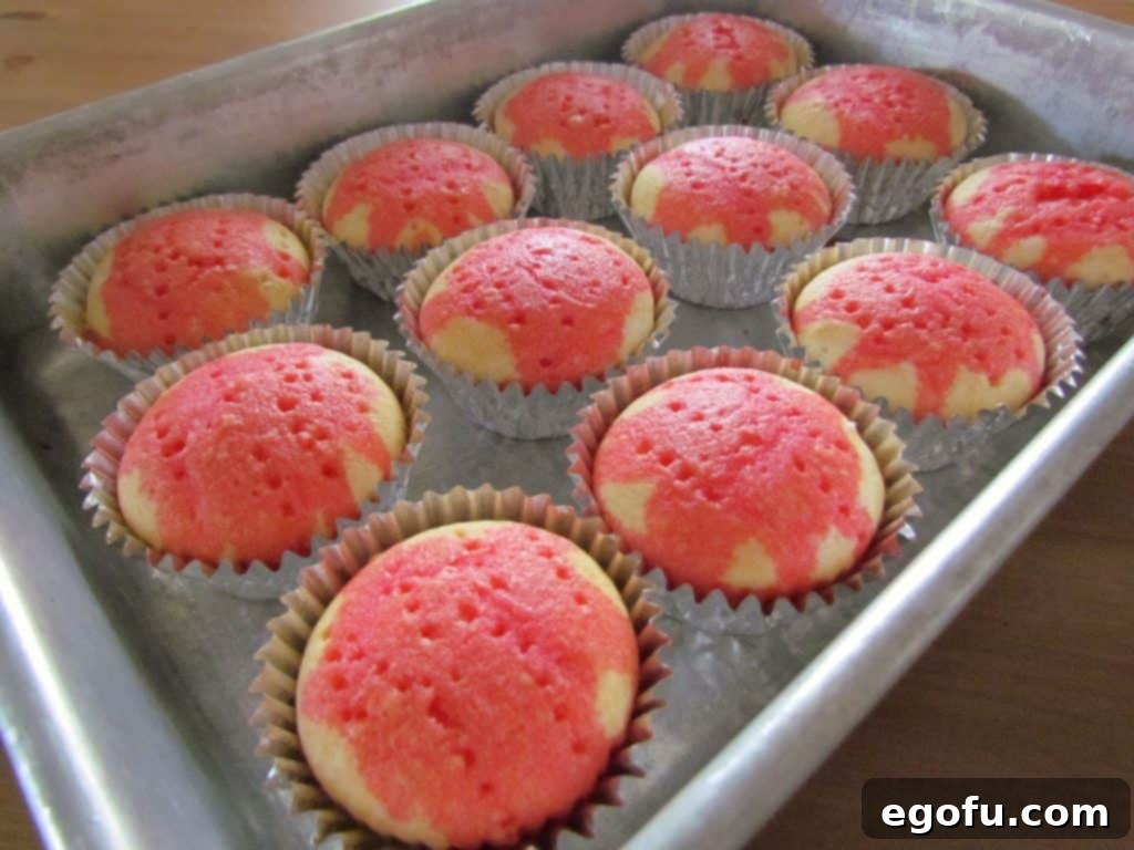 Strawberry Burst Poke Cupcakes 7 A tray of a dozen cupcakes with holes poked and strawberry Jell-O mixture poured over them, ready for chilling.