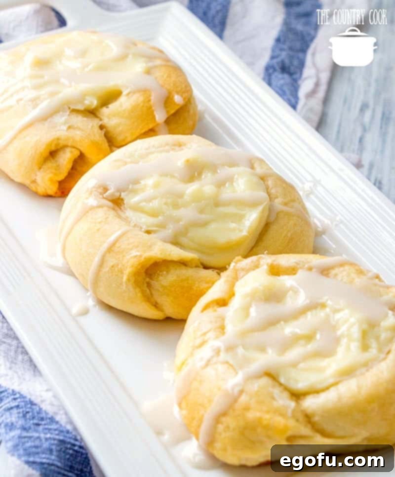 Effortless Cheesy Danishes 2 Easy Cheese Danishes made with crescent rolls and layered on a white platter.