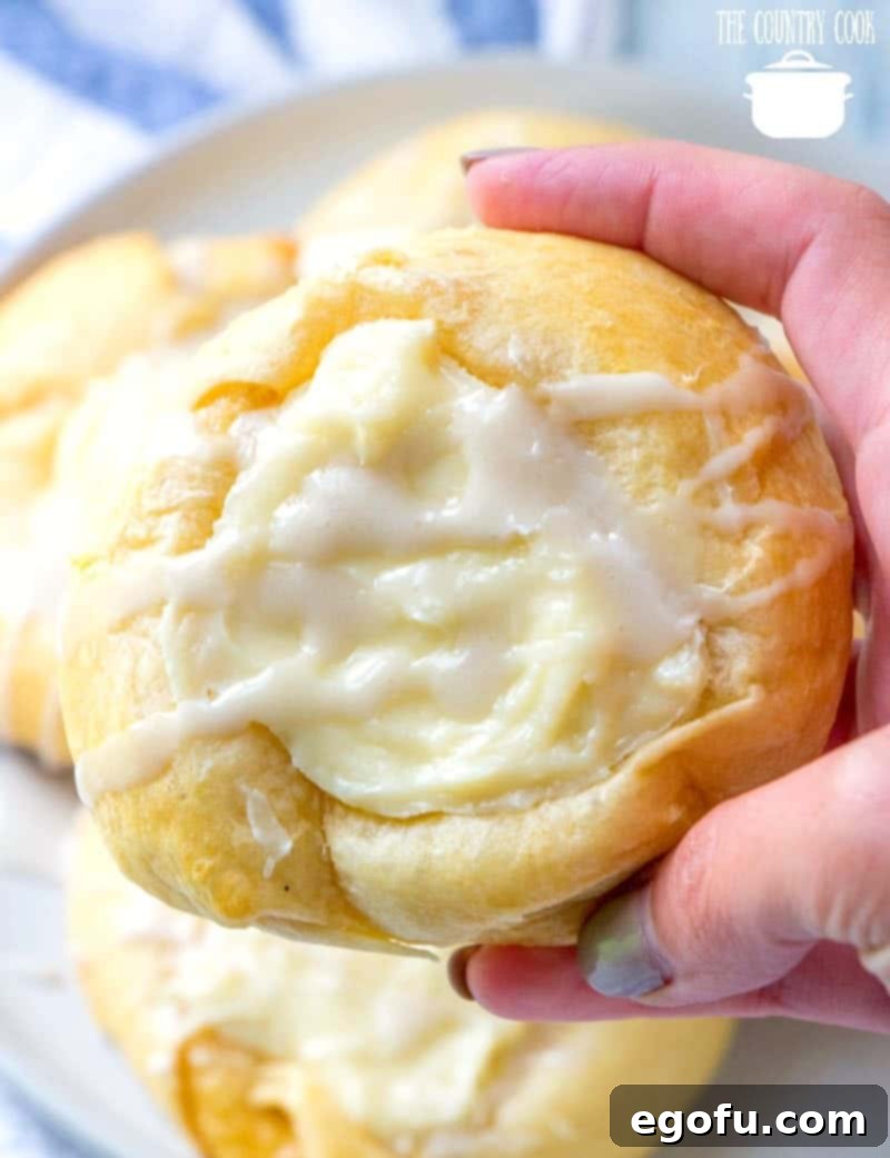 Effortless Cheesy Danishes 12 a hand holding up a cheese danish.