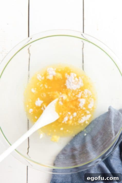 Pineapple Mandarin Ambrosia Cake 14 Instant pudding mix being stirred with pineapple juice in a bowl.