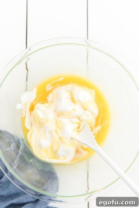 Pineapple Mandarin Ambrosia Cake 15 Defrosted Cool Whip being added on top of the pineapple pudding mixture.