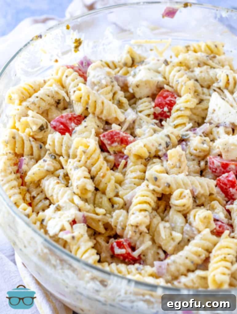A finished Caesar Basil Pasta Salad presented in a large clear bowl, showcasing its vibrant colors and creamy texture.