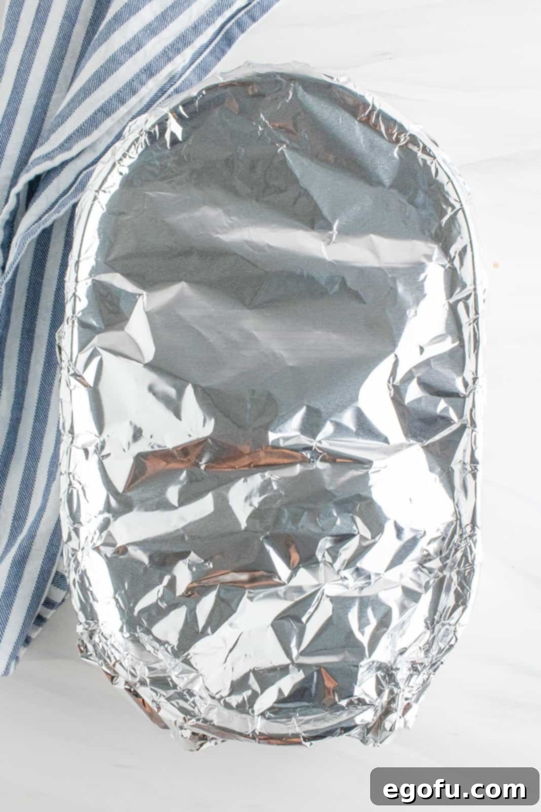 Baking dish shown covered in aluminum foil, ready for the oven.