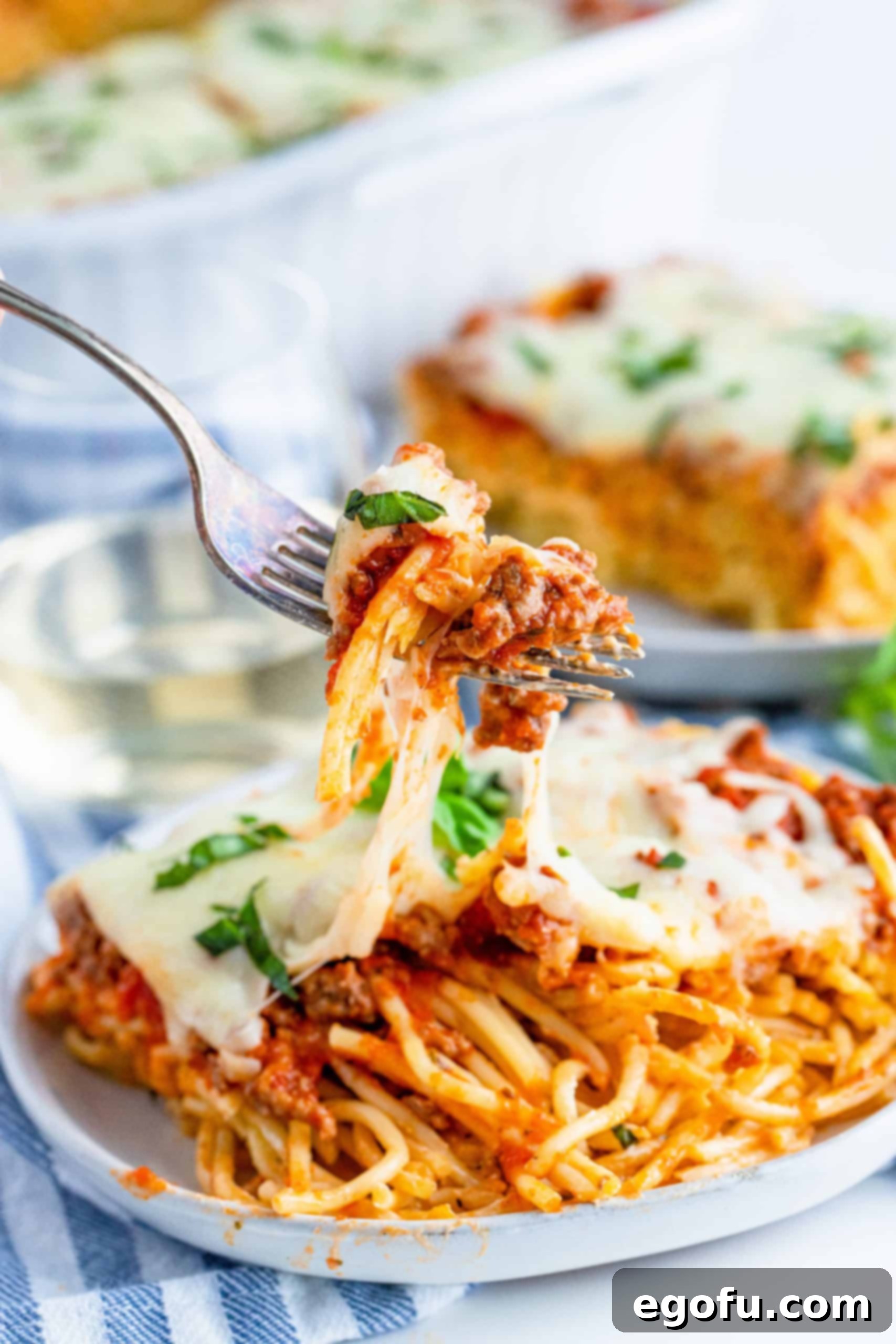 Close up photo of a fork pulling up a bite of Baked Spaghetti, showing the texture and deliciousness.
