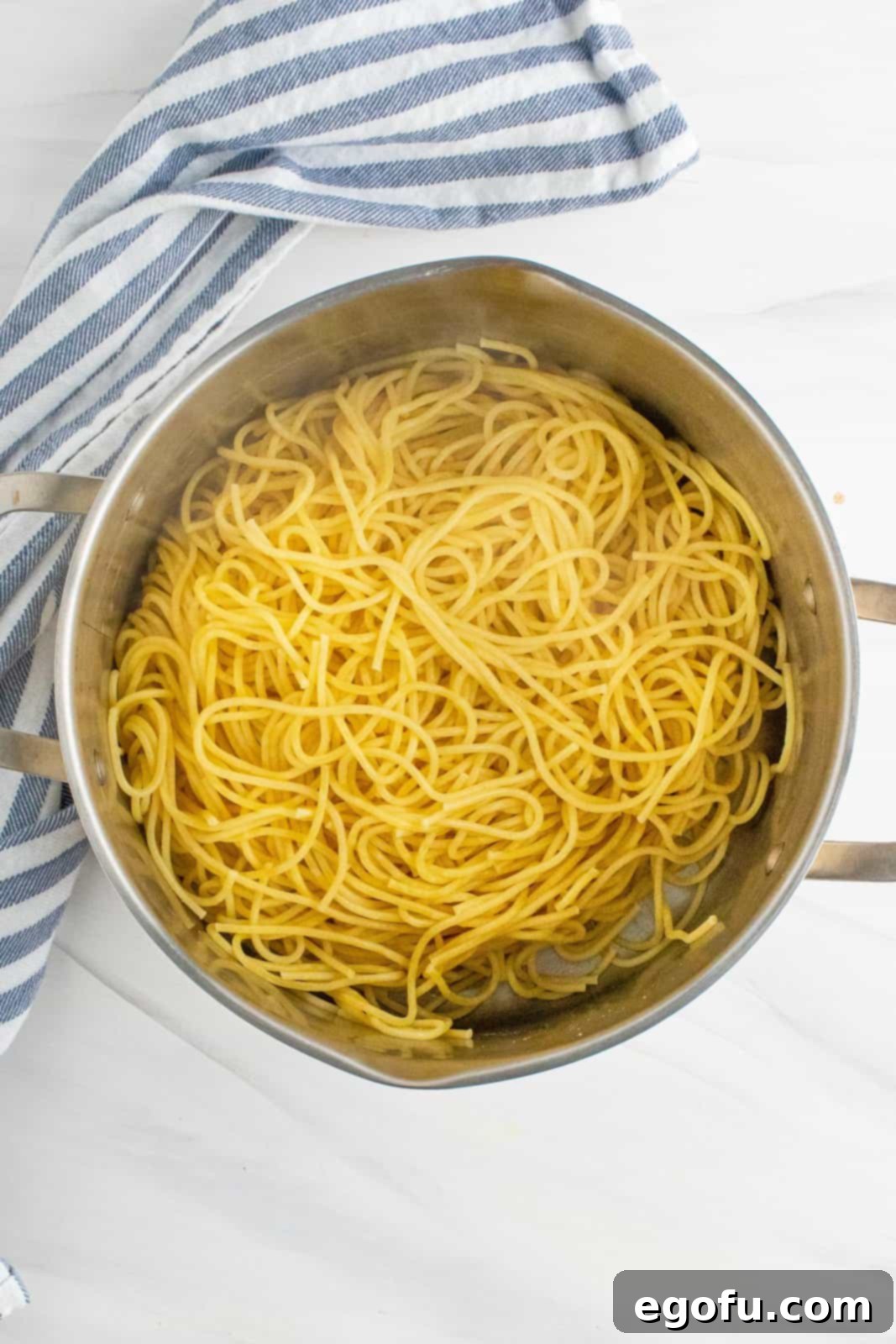 Cooked spaghetti noodles being drained in a colander.