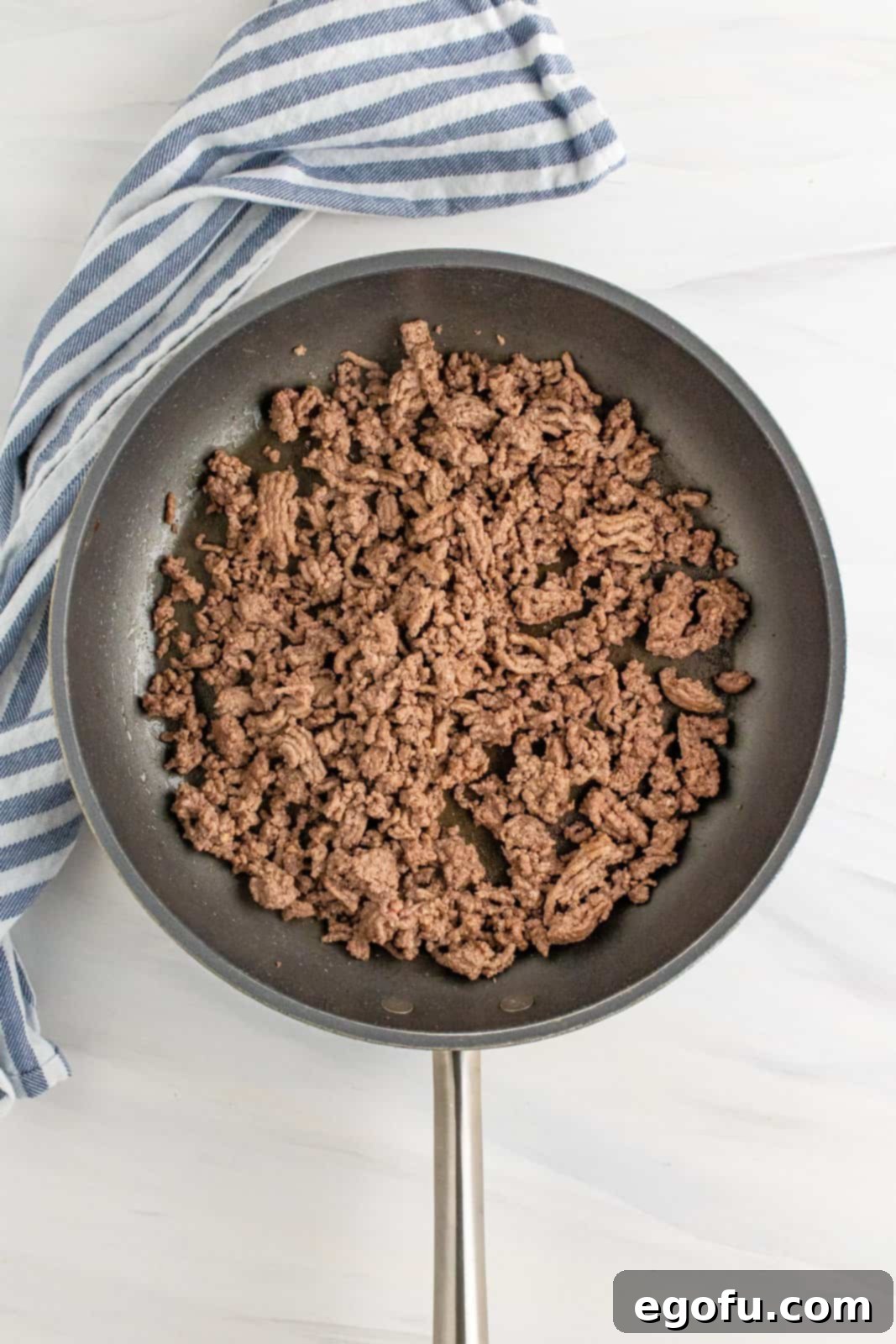 Browned and crumbled cooked ground beef in a large skillet, ready for the sauce.