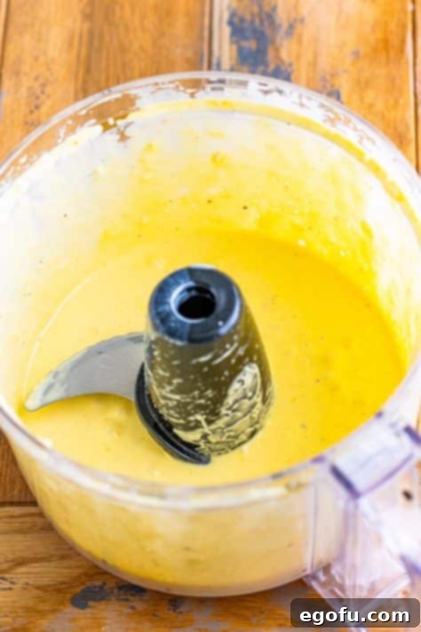 A food processor containing perfectly blended, smooth homemade Caesar Salad Dressing, ready for chilling.