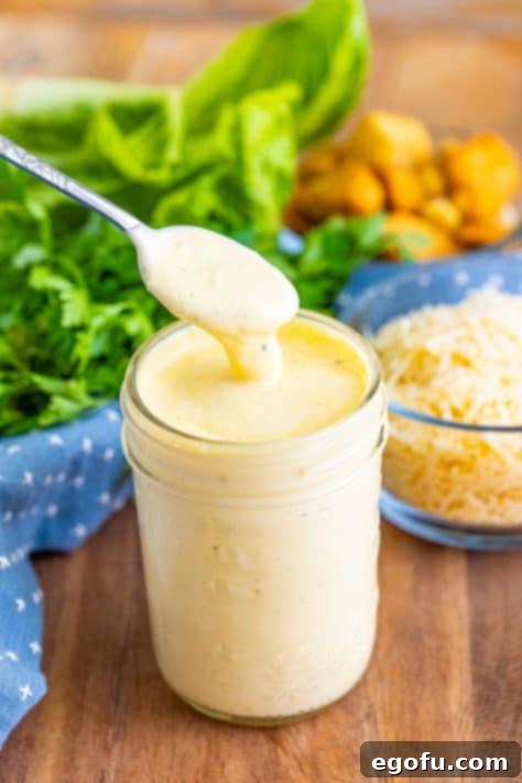 A small mason jar filled with freshly made homemade Caesar salad dressing, ready for refrigeration.