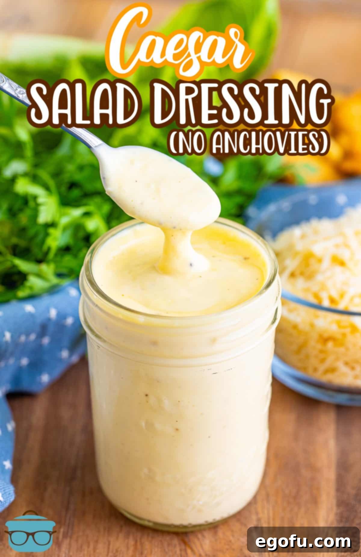 A spoon delicately holding a scoop of creamy homemade Caesar Salad Dressing, positioned above a glass jar filled with the dressing.