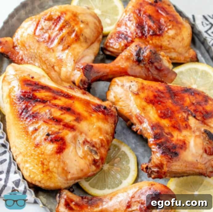 Huli Huli chicken shown after it has been grilled on a metal platter with sliced lemons.