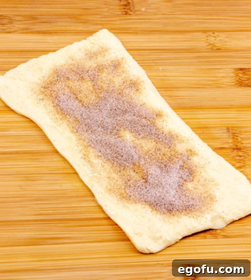 Golden Apple Danish Pastries 6 Cinnamon sugar being sprinkled on top of buttered crescent rolls.