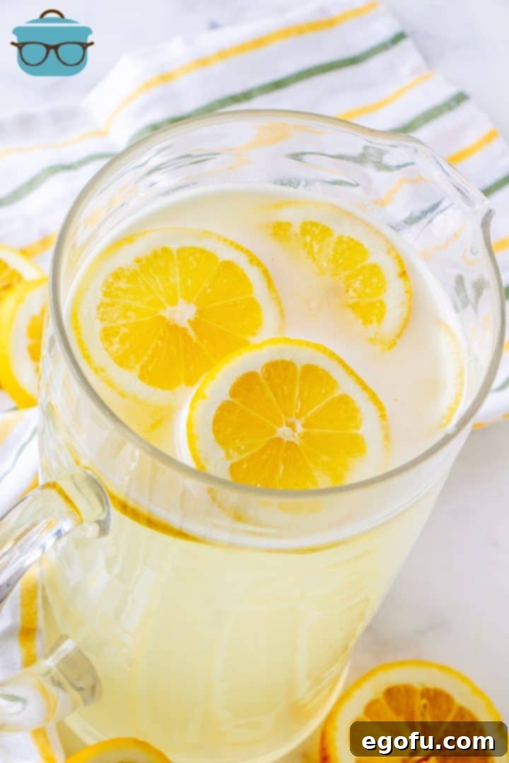 Large glass pitcher filled with fresh squeezed homemade lemonade and garnished with sliced lemons