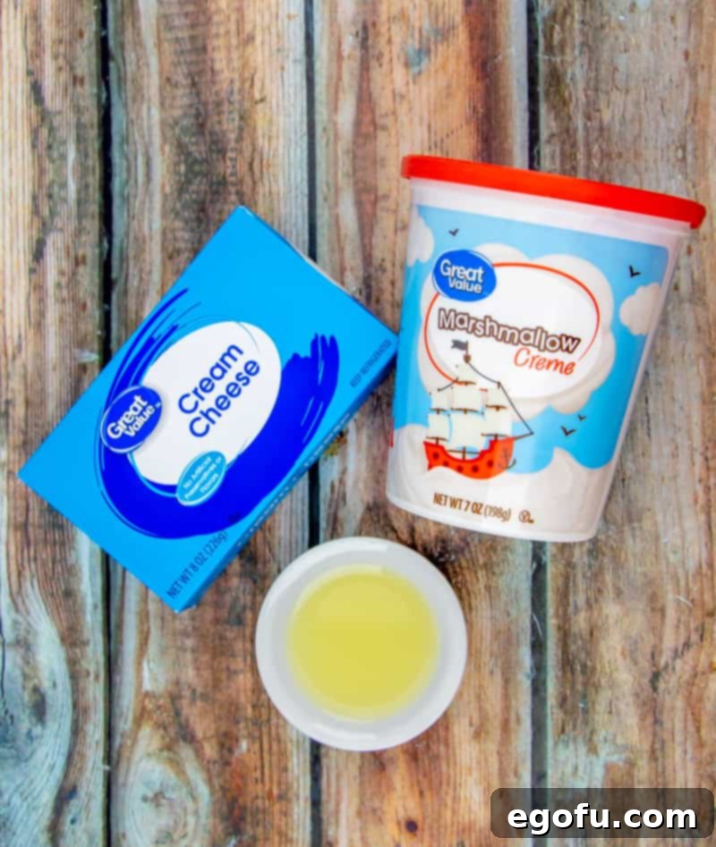 The three essential ingredients for creamy fruit dip: a block of cream cheese, a jar of marshmallow fluff, and a small bowl of fresh lemon juice.