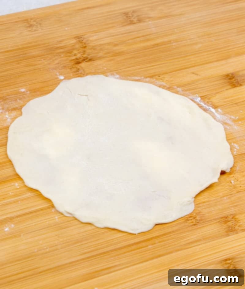Soft Homemade Flour Tortillas 7 rolled out homemade flour tortilla dough on a wooden cutting board, demonstrating the desired thinness.