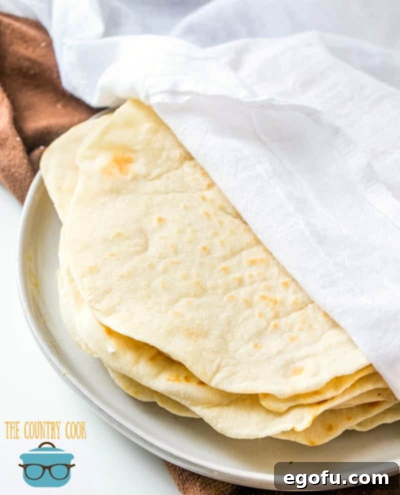 Soft Homemade Flour Tortillas 9 Homemade Flour Tortillas staying warm in between clean white dish towels, preserving their softness.