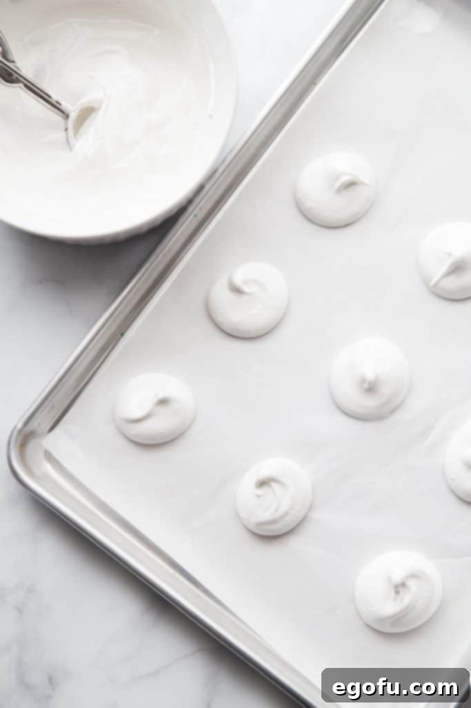 Homemade vanilla meringues before baking on a cookie sheet.