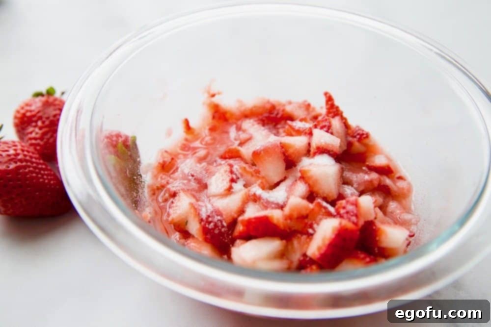diced strawberries mixed with sugar in a glass bowl.