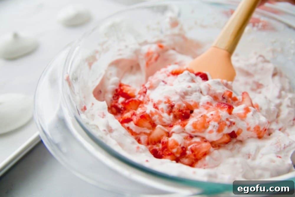 stirring freshly sweetened strawberries into homemade whipped cream and crushed meringue cookies.