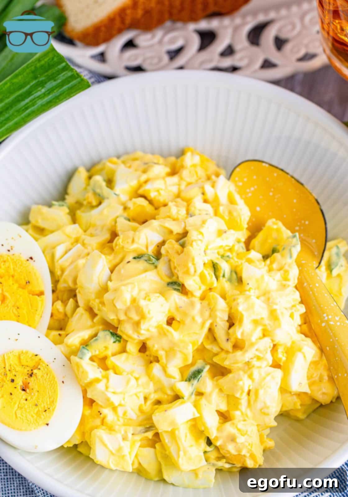 Irresistible Homemade Egg Salad 2 A beautifully presented bowl of creamy classic egg salad, garnished with fresh herbs, alongside a perfectly sliced hard-boiled egg.