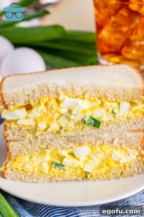 Irresistible Homemade Egg Salad 12 two egg salad sandwiches stacked on top of each other on a white plate.