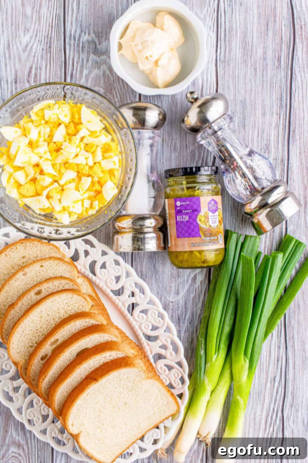 Irresistible Homemade Egg Salad 3 All the essential ingredients for egg salad laid out: chopped hard-boiled eggs, mayonnaise, sweet relish, salt, pepper, and sliced green onions, ready for mixing.