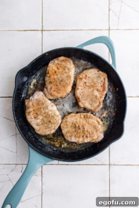Flipped over pork chops in pan showing browning.