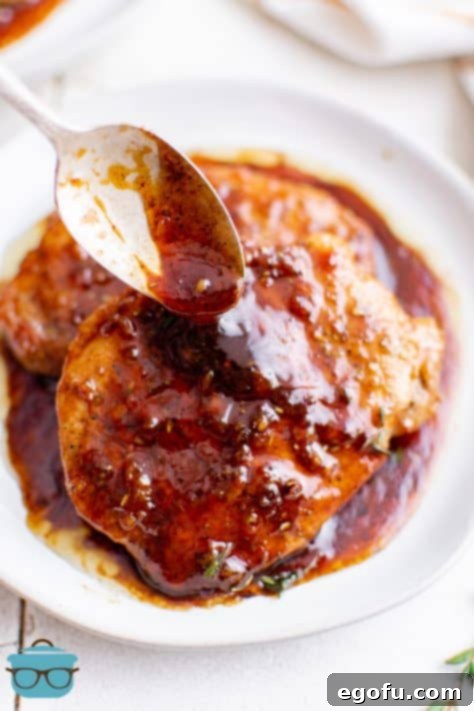 Sauce being spooned over Honey Garlic Pork Chops stacked on plate.