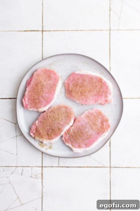 Pork chops on plate seasoned with seasonings.