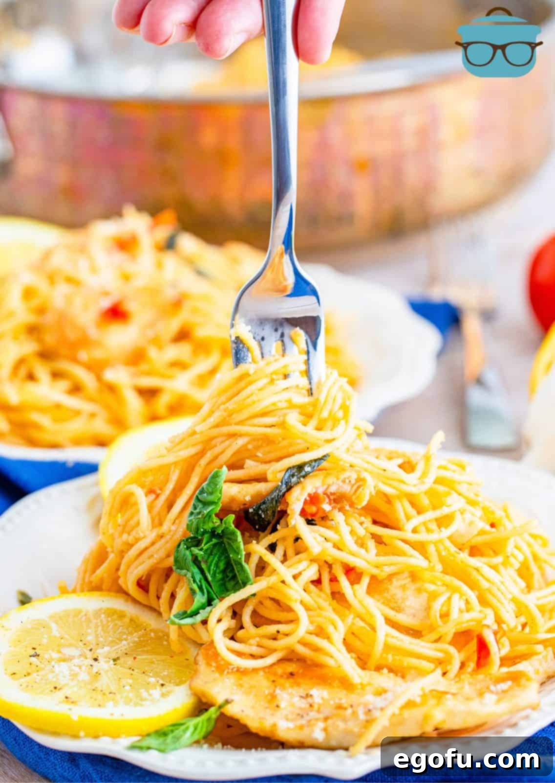 Fork twirling Lemon Chicken Pasta on white plate garnished.