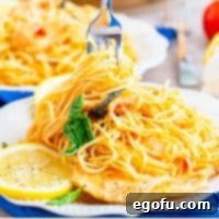 Square image close up of Lemon Chicken Pasta being twirled on fork on white plate.