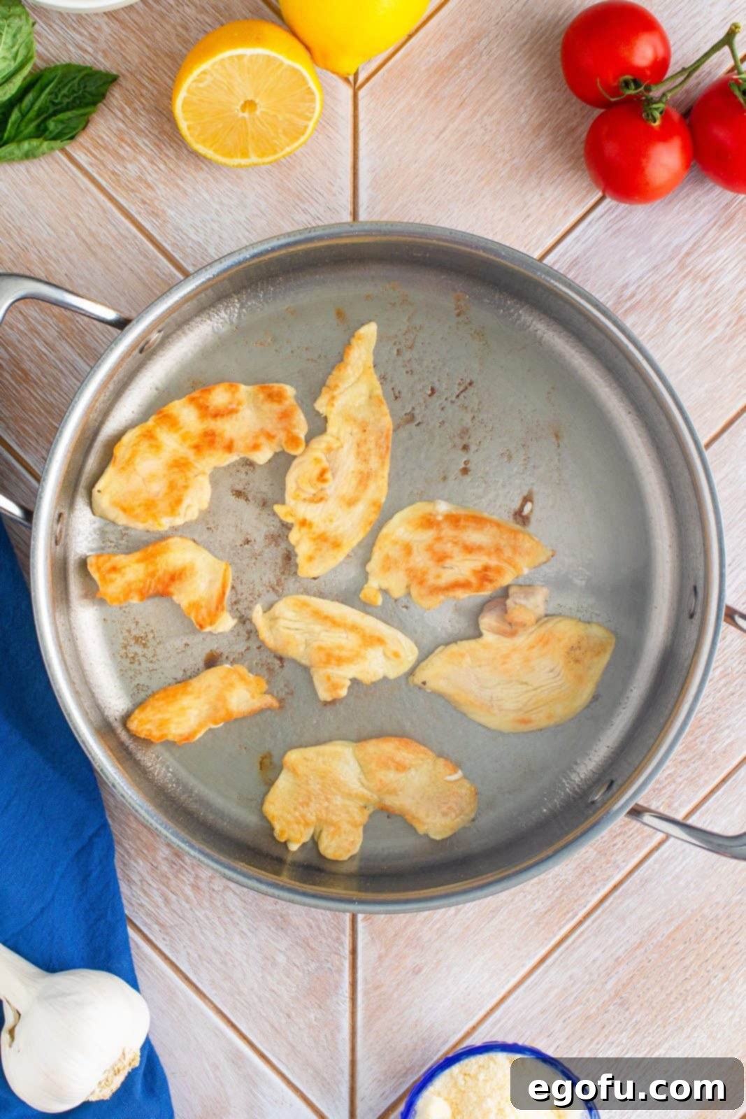 Chicken pieces being browned with olive oil in pan.